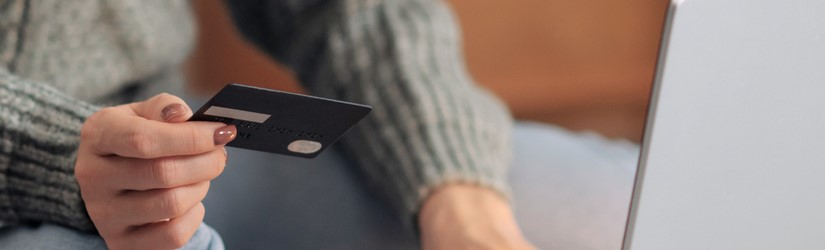 Main féminine sur l'ordinateur portable avec la carte de crédit